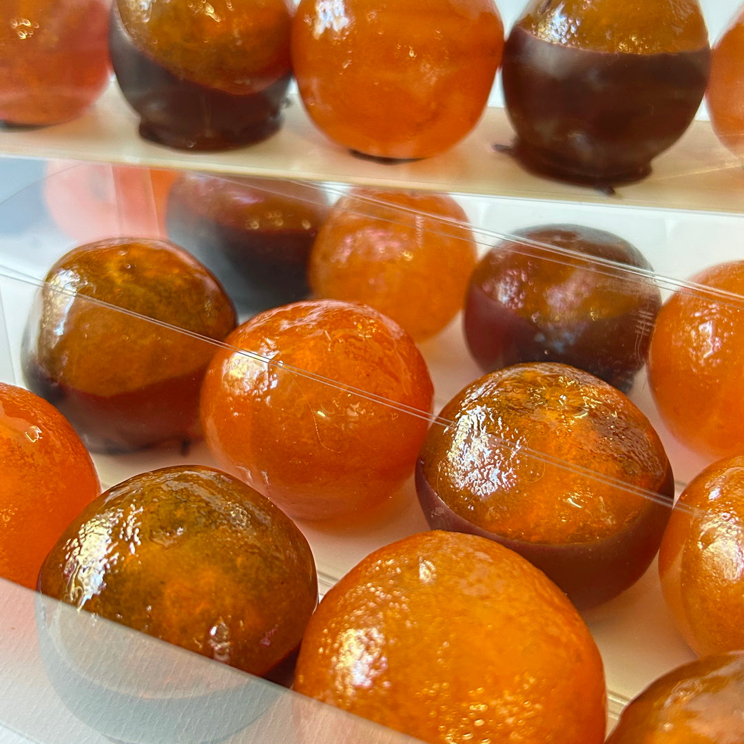 Joyaux de Corse en gros plan, fruits confits d'agrumes brillants, certains trempés dans le chocolat